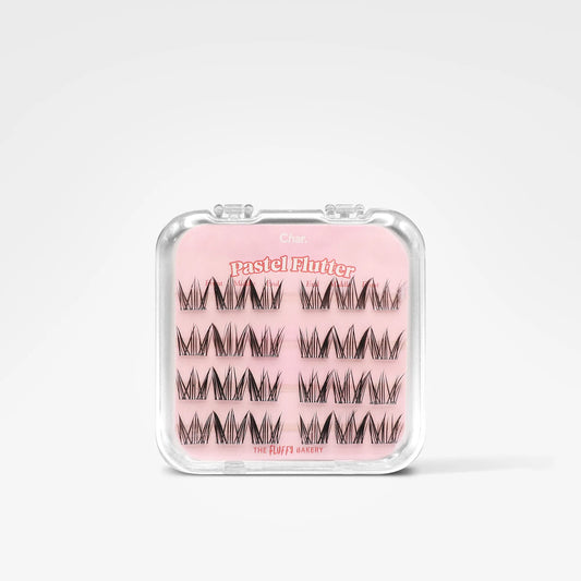 A clear plastic clamshell case containing three rows of black eyelash clusters on a pink backing card. The card reads 'Pastel Flute' and 'The Hair's Axxessy'.