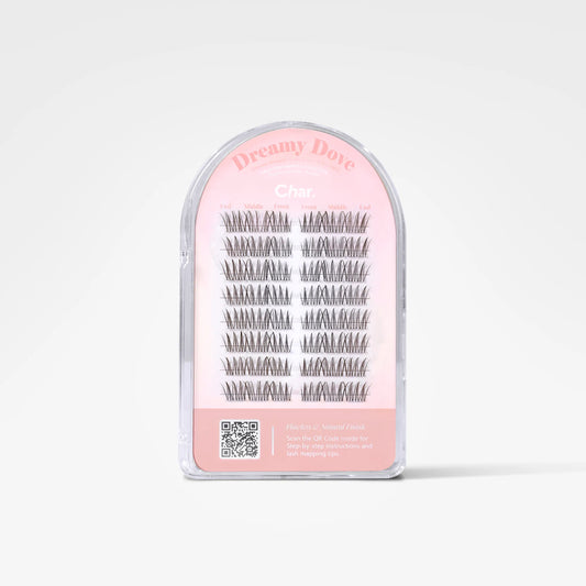 A clear plastic arch-shaped package containing multiple pairs of black false eyelashes on a pink backing card. The card reads 'Dreamy Dove' and 'Char.