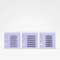 Three slim rectangular product boxes with white borders and pale lavender fronts are arranged side by side on a clean white background. Each box contains many small black-and-white illustrated figures or symbols arranged in rows.