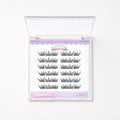 A package of false eyelashes in a clear plastic case with a white insert. The insert shows 12 pairs of black false eyelashes arranged in two columns, with a lavender header and footer.