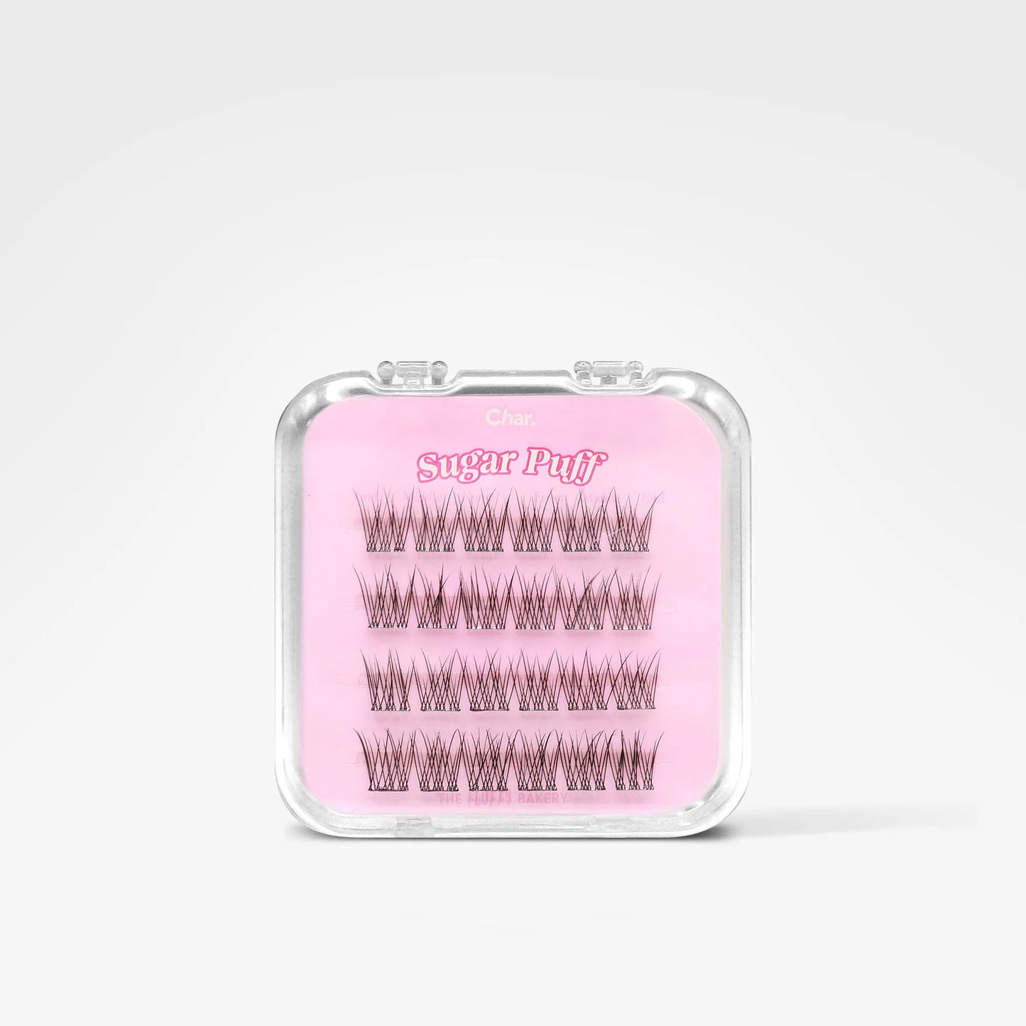 A clear plastic clamshell case containing false eyelash clusters on a pink backing card labeled 'Sugar Puff' and 'Clás', photographed on a clean white background.