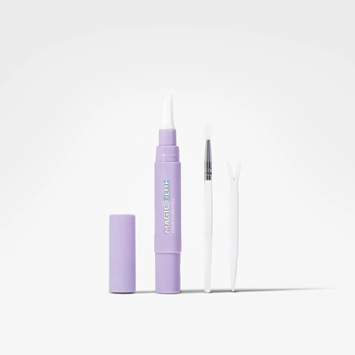 A lavender purple beauty kit containing a tube of 'Magic Glue' with its cap removed, a small white spatula, and a white Y-shaped tool, displayed on a clean white background.
